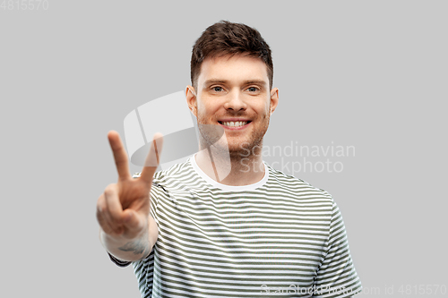 Image of young man showing peace over grey background