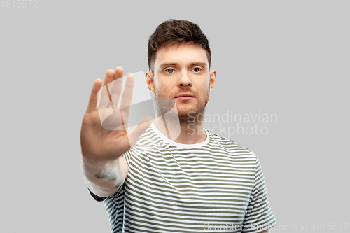 Image of serious young man showing stop gesture