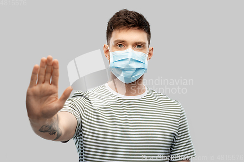 Image of man in protective medical mask making stop gesture