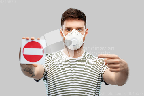 Image of man in respirator mask showing stop sign