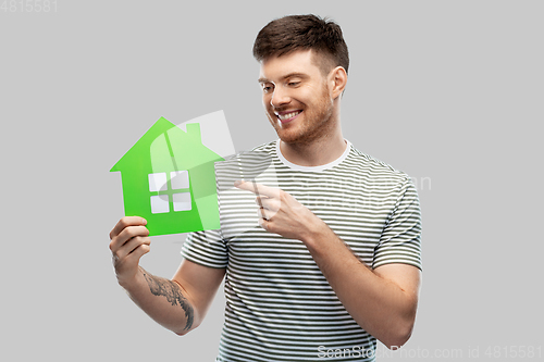 Image of smiling young man holding green house icon