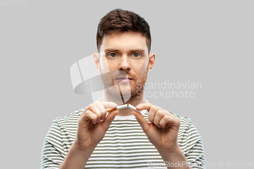 Image of young man in striped t-shirt braking cigarette