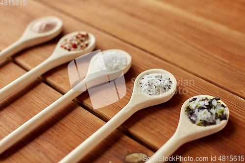 Image of spoons with salt and spices on wooden table