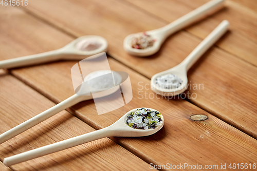 Image of spoons with salt and spices on wooden table