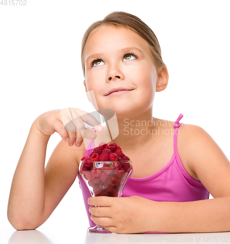 Image of Happy little girl is eating raspberries