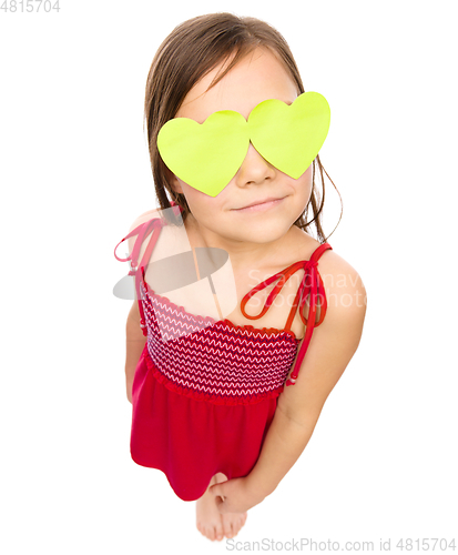 Image of Little girl is holding hearts over her eyes