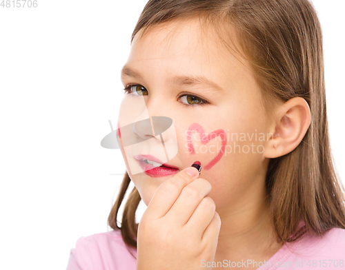 Image of Little girl is applying lipstick on her cheek