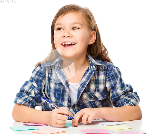 Image of Girl is writing on color stickers using pen