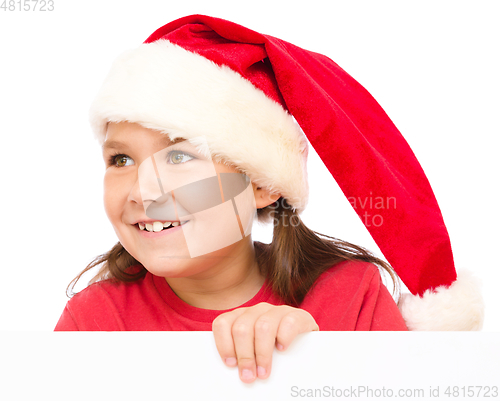 Image of Little girl in santa hat is holding blank board