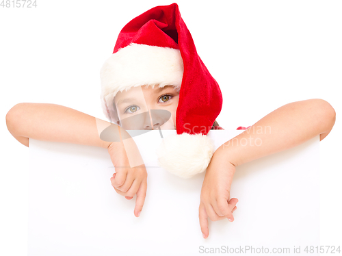 Image of Little girl in santa hat is holding blank board