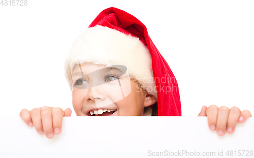 Image of Little girl in santa hat is holding blank board