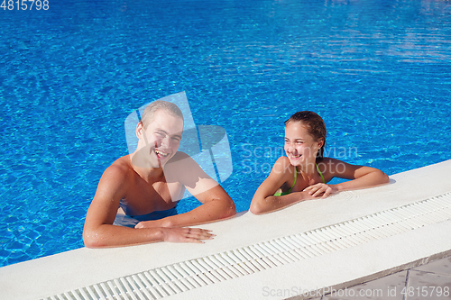 Image of boy and girl having fun in swimming pool
