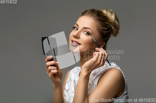 Image of beautiful girl applying makeup