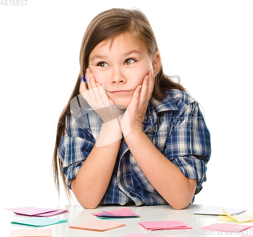 Image of Girl is writing on color stickers using pen
