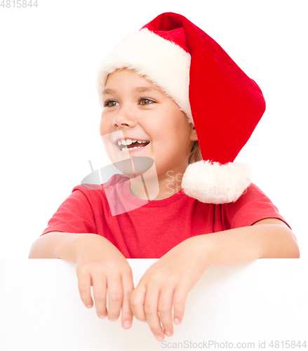 Image of Little girl in santa hat is holding blank board