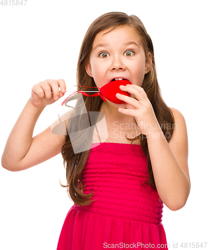 Image of Portrait of a little girl biting red heart