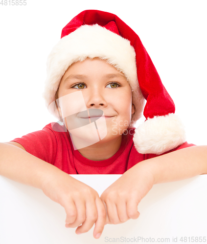 Image of Little girl in santa hat is holding blank board