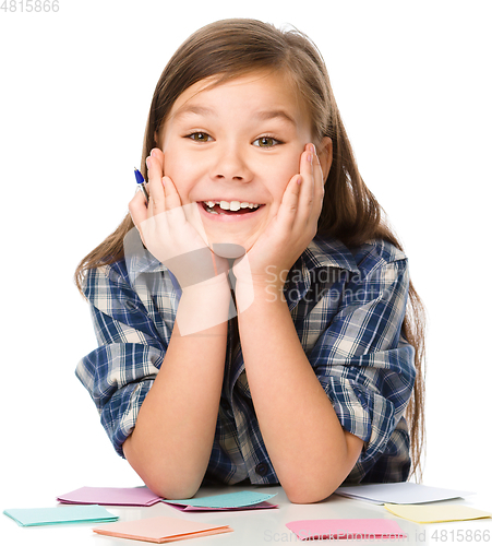 Image of Girl is writing on color stickers using pen