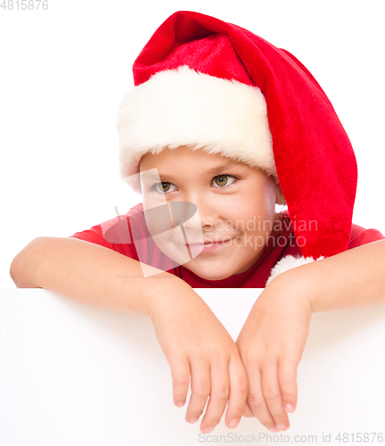 Image of Little girl in santa hat is holding blank board