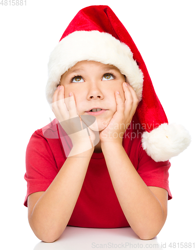 Image of Little girl in santa hat is daydreaming