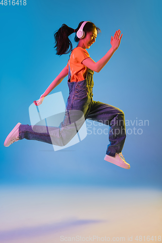 Image of Asian young woman\'s portrait on blue studio background in neon. Concept of human emotions, facial expression, youth, sales, ad.