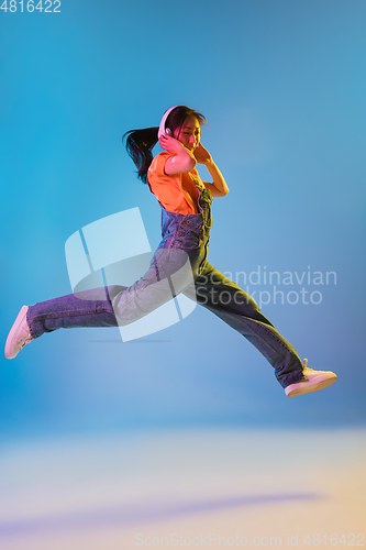 Image of Asian young woman\'s portrait on blue studio background in neon. Concept of human emotions, facial expression, youth, sales, ad.