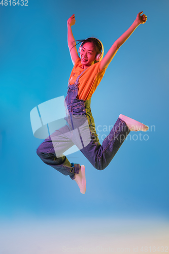 Image of Asian young woman\'s portrait on blue studio background in neon. Concept of human emotions, facial expression, youth, sales, ad.