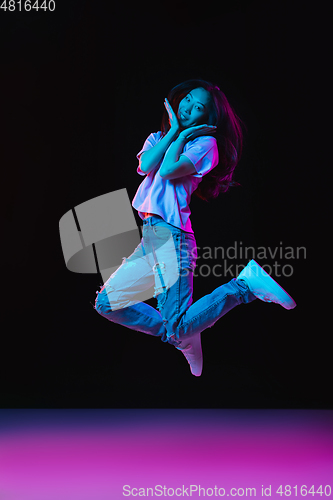 Image of Asian young woman\'s portrait on dark studio background in neon. Concept of human emotions, facial expression, youth, sales, ad.