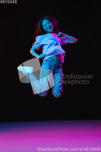 Image of Asian young woman\'s portrait on dark studio background in neon. Concept of human emotions, facial expression, youth, sales, ad.