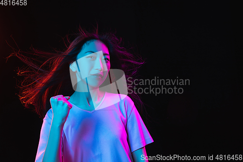 Image of Asian young woman\'s portrait on dark studio background in neon. Concept of human emotions, facial expression, youth, sales, ad.