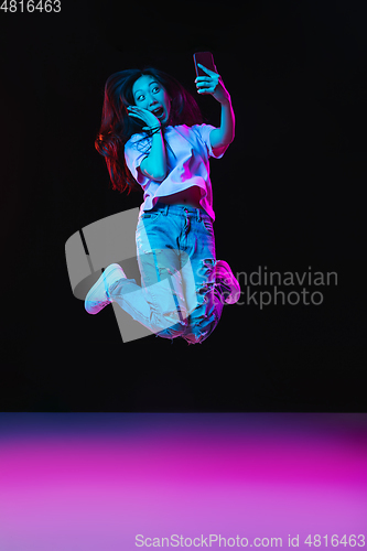 Image of Asian young woman\'s portrait on dark studio background in neon. Concept of human emotions, facial expression, youth, sales, ad.