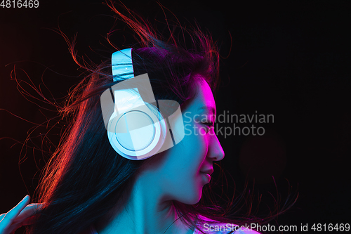Image of Asian young woman\'s portrait on dark studio background in neon. Concept of human emotions, facial expression, youth, sales, ad.