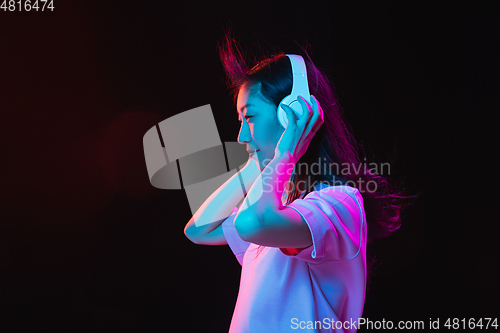 Image of Asian young woman\'s portrait on dark studio background in neon. Concept of human emotions, facial expression, youth, sales, ad.