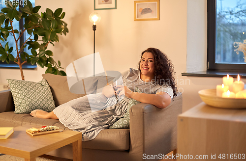 Image of happy woman drinking red wine at home in evening