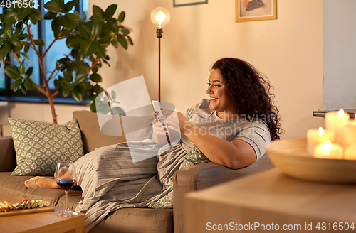 Image of woman with smartphone at home in evening