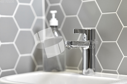 Image of close up of water tap with liquid soap on sink