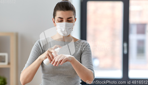 Image of close up of woman in mask spraying hand sanitizer