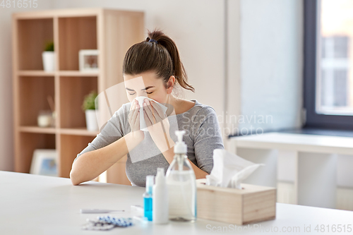 Image of sick woman with medicine blowing nose to wipe