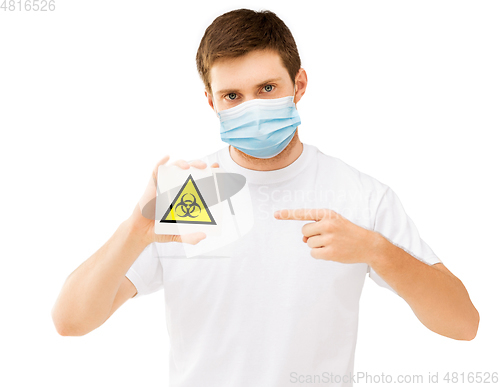 Image of man in medical mask holding boihazard caution sign