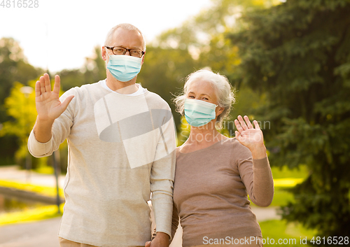 Image of senior couple in protective medical masks at park