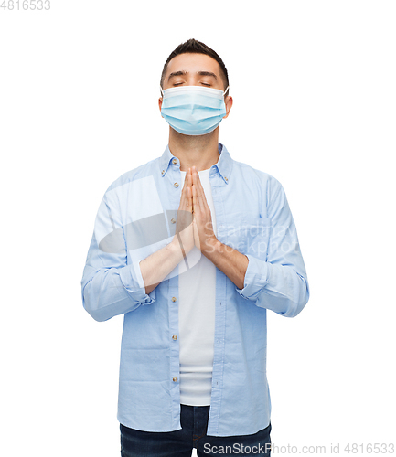 Image of young man in protective medical mask praying