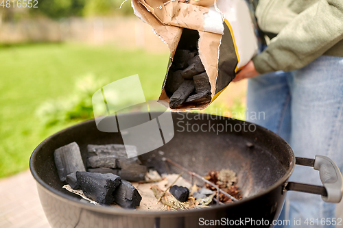 Image of close up of man pouring charcoal to brazier