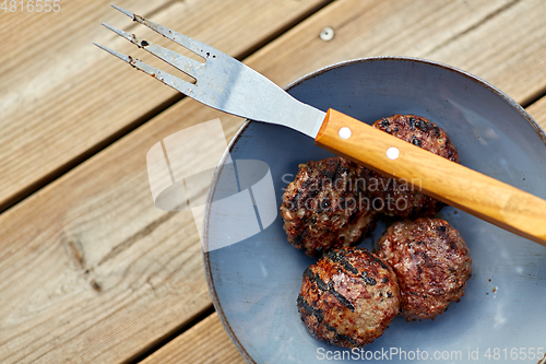 Image of roasted meat cutlets on plate with barbeque fork