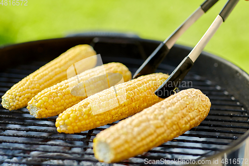 Image of close up of corn roasting on grill outdoors