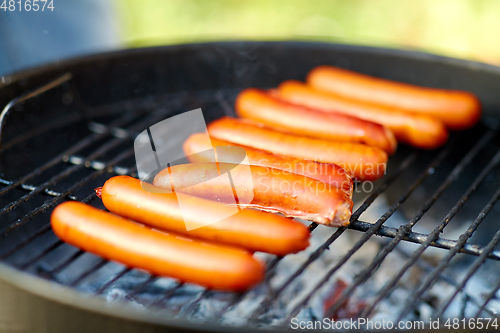 Image of meat sausages roasting on hot brazier grill