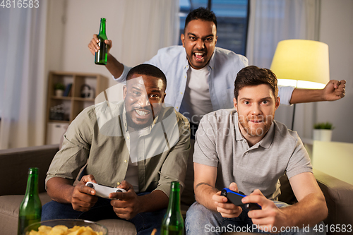 Image of happy friends playing video games at home at night