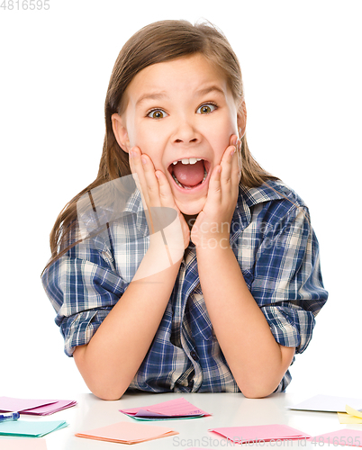 Image of Girl is writing on color stickers using pen