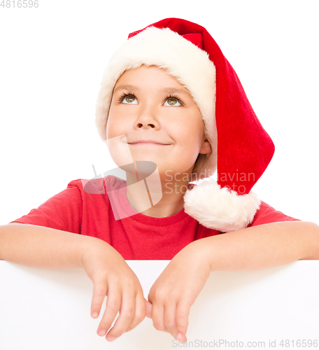 Image of Little girl in santa hat is holding blank board