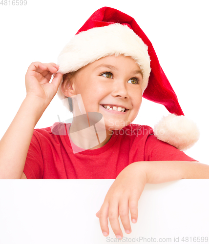 Image of Little girl in santa hat is holding blank board