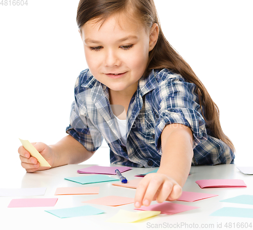 Image of Girl is writing on color stickers using pen